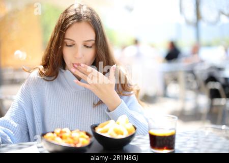 Restaurantgast isst und leckt Finger auf einer Terrasse Stockfoto