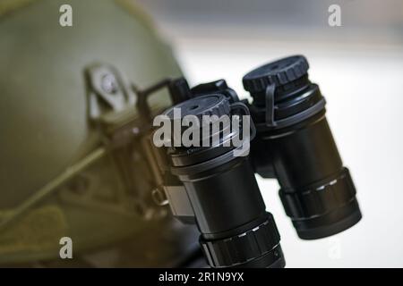 Fernglas der Armee mit Nachtsicht auf einem Soldatenhelm. Optisches Gerät auf einem Militärhelm zur Verfolgung im Krieg Stockfoto