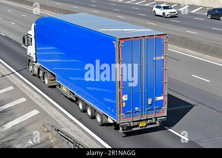 Unmarkierte saubere lkw-Lieferkette weißer LKW und blauer knickgelenkter Auflieger Seitenansicht und Rückansicht der Antenne auf der britischen autobahn M25 Stockfoto