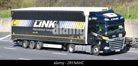 Schwarzer Lkw-Motorwagen der DAF XF lkw-Serie und leicht zugänglicher Auflieger der polnischen Wielton Group für Link International Transport auf der Autobahn M25 UK Stockfoto