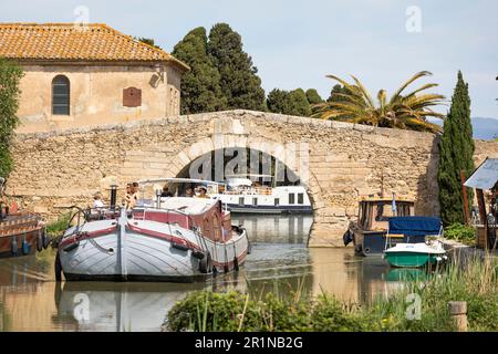 Eine Familie segelt auf einem Boot, vorbei an einer Brücke am Canal du Midi in Homps, Frankreich Stockfoto
