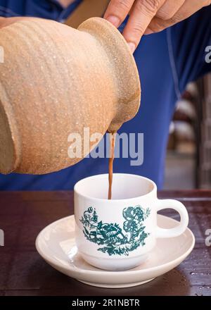 Ein Mann, der Kaffee aus dem Claypot gießt. Nahaufnahme. Stockfoto