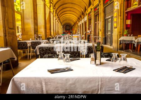 Leeres Straßencafé im Sommer mit überdachten weißen Tischen in barcelona Stockfoto