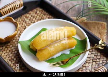 Baby-Bananen in Sirup, garniert mit Kokosmilch, serviert auf einem Bambustablett aus nächster Nähe - thailändisches Dessert namens Kluay Kai Cheum Stockfoto