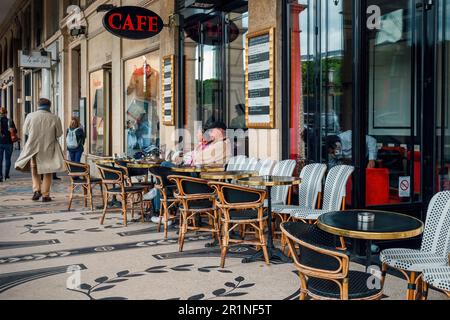 Ein Paar sitzt in einem Café im Freien mit traditionellen altmodischen Tischen auf der Straße in Paris, Frankreich. Stockfoto