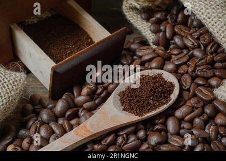 Gemahlener Kaffee auf einem Löffel und geröstete Kaffeebohnen in einem Sack. Stockfoto