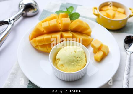 Mangoeis mit reifer Mango an der Seite in einem weißen Gericht - Nahaufnahme des Desserts Stockfoto