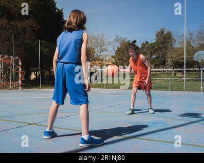 Ein Einzelgespräch zwischen zwei jungen Basketballspielern auf einem Platz im Freien an einem sonnigen Tag. Stockfoto