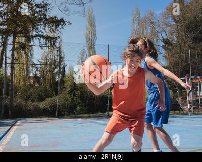 Basketballspieler, der einen anderen Spieler in einem Spiel im Freien dribbelt. Stockfoto