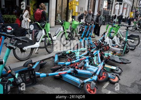Am Straßenrand stehen Limettenfahrräder an, und die Dott eScooter sind am 12. Mai 2023 in London, England, mit dem Domino-Effekt umgefallen. Stockfoto