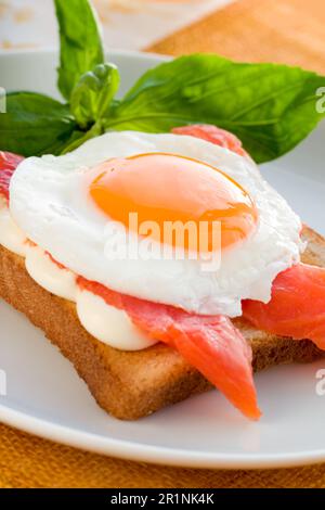 Toast mit Spiegelei, gesalzenem Fisch und Frischkäse auf dem Teller Stockfoto