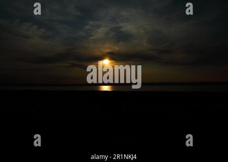 Dramatisch bewölkter Himmel bei Sonnenuntergang, dunkle Wolken, Sonne scheint durch eine Wolkenlücke, Neusiedlsee, Burgenland, Österreich Stockfoto