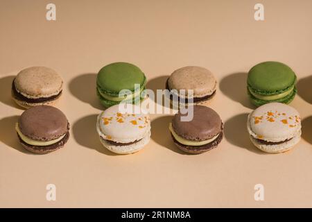 Satz Makronen auf beigefarbenem Hintergrund mit hartem Licht Stockfoto