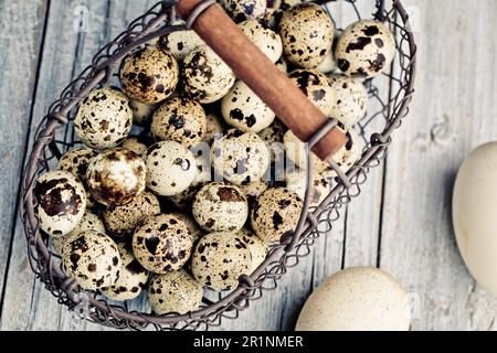 Kleine gefleckte Wachteleier in einem alten Metallkorb Stockfoto