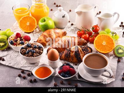 Frühstück mit Kaffee, Orangensaft, Croissants, Ei, Müsli und Obst. Ausgewogene Ernährung Stockfoto