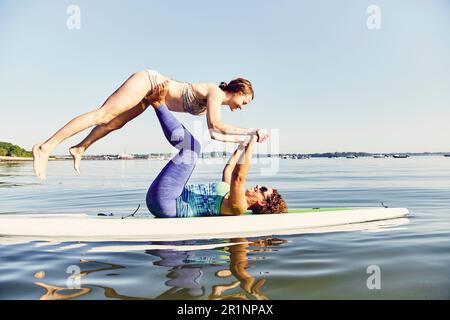 Zwei junge Frauen, die Yoga auf einem Stehpaddelbrett machen Stockfoto