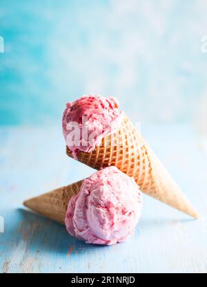 Eiscreme mit Himbeere in Waffel auf blauem Hintergrund Stockfoto