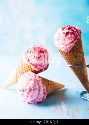 Eiscreme mit Himbeere in Waffel auf blauem Hintergrund Stockfoto