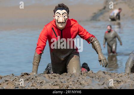 Teilnehmer an Maske Teilnahme am Maldon Mud Race in Maldon, Essex, Großbritannien, im Schlamm des Flusses Blackwater. Traditionelle Wohltätigkeitsveranstaltung Stockfoto