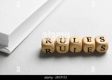 Wortregeln aus Holzwürfeln mit Buchstaben und Buch auf weißem Tisch Stockfoto