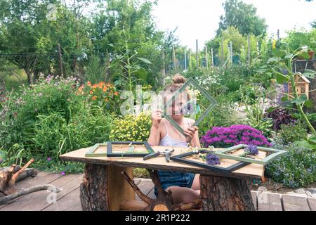 Ein bezauberndes blondes Mädchen, das im Garten sitzt und lavendelfarbene Bilder kreiert Stockfoto