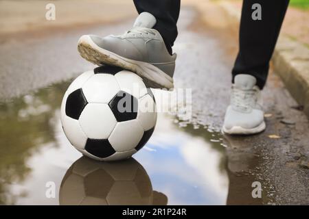 Mann mit Fußball in der Nähe der Pfütze, Nahaufnahme Stockfoto