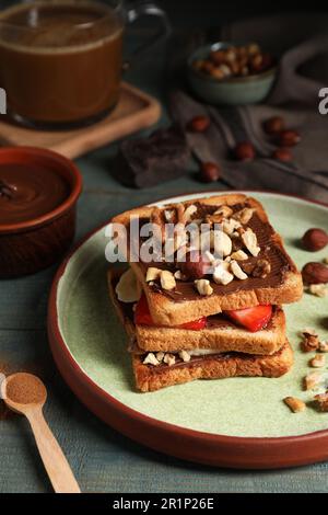 Leckere Toasts mit Schokoladenaufstrich, Nüssen, Erdbeeren und Banane, serviert auf einem Holztisch Stockfoto