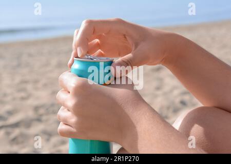 Frau öffnet Aluminiumdose mit Getränk am Strand, Nahaufnahme Stockfoto