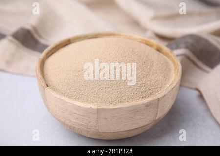 Granulat in einer Holzschüssel auf einem hellgrauen Tisch, Nahaufnahme Stockfoto