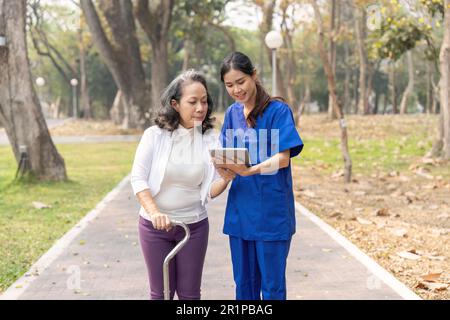 Krankenschwester zeigt der Seniorin auf einem digitalen Tablet im Krankenhaus-Park einen medizinischen Bericht Stockfoto