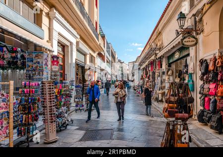 Athen, Griechenland - Januar 7 2023: Adrianou Street in Plaka, eine geschäftige Fußgängerzone mit Geschäften und Straßenbahnen, Cafés. Stockfoto