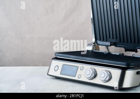 Elektrischer Grill. Moderne Küche tragbares Grillgerät für moderne Küche zum Grillen von Fleisch, Gemüse und Snacks zum Abendessen oder zur Party auf hellgrauem Hintergrund Stockfoto