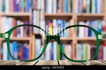 Brille vor verschwommenem Bücherregal Stockfoto