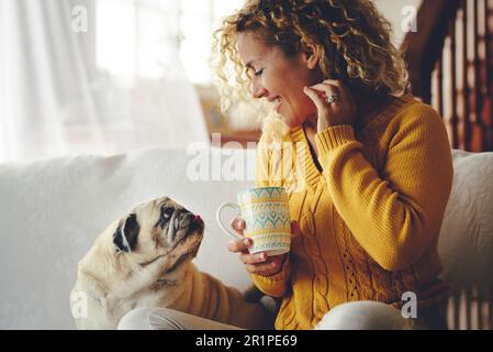 Frau, blond, Locken, Lächeln, Sofa, Sitz, Blickkontakt, Hund, Pug, Stockfoto