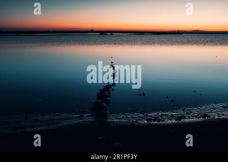 Neblige Landschaft am ruhigen See bei Sonnenaufgang. Konzept eines wunderschönen, malerischen Wasserortes und stimmungsvollem Licht. Reiseziel. Vertikale Zusammensetzung. Bild einer ruhigen Natur. Entspann Dich. Abendfarbe, Abenddämmerung Stockfoto