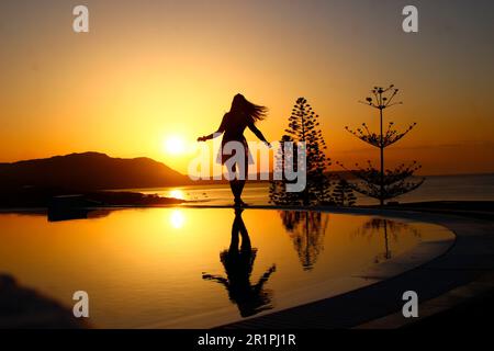 Junge Frau am Pool bei Sonnenaufgang, Kiotari, Rhodos, Griechenland Stockfoto