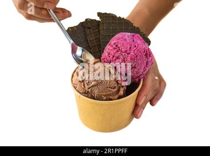 Hand mit einem Löffel, der ein Stück hausgemachtes Eis, crem Tiramisu und Hibiscus, isoliert auf weißem Hintergrund, hält Stockfoto