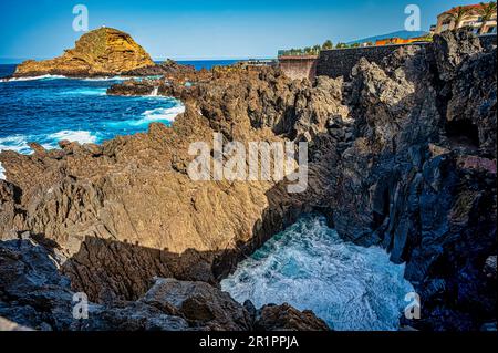 Eine ruhige Küstenlandschaft mit einem weitläufigen felsigen Strand und glitzerndem blauen Ozean mit schroffen Felsen, die von der Küste ragen Stockfoto