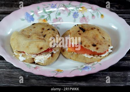 Feta-Weißkäse mit Scheiben Tomaten in einem traditionellen ägyptischen Minibrot mit Weizenkleie und Mehl, einem kleinen Aish Baladi oder einem kleinen Bread Ba Stockfoto