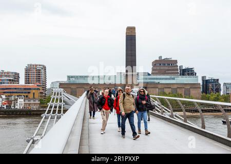 Fußgänger auf der Millennium Bridge an einem bedeckten und windgepeitschten Frühlingstag in London, Großbritannien Stockfoto