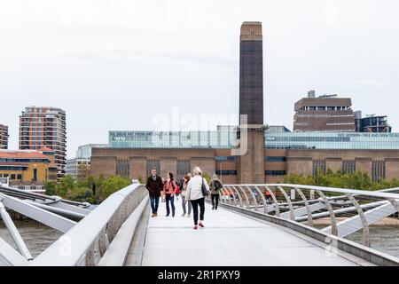 Fußgänger auf der Millennium Bridge an einem bedeckten und windgepeitschten Frühlingstag in London, Großbritannien Stockfoto