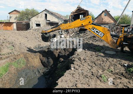 ZOLOCHIV, UKRAINE - 14. MAI 2023 - ein Bagger gräbt den Boden nach dem Raketenangriff Russlands, das angeblich S-300-Boden-Luft-Raketen benutzte Stockfoto