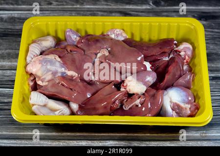 Rohe Hühnerleber, Muskelmagen und Herzen, selektiver Fokus frischer Leber, Muskelmagen und Herz von Hühnern voll mit Protein in einer gelben Einwegplatte ist Stockfoto