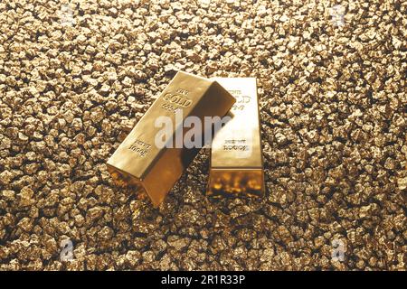 Finanzkonzept. Zwei glänzende Goldbarren auf einem Haufen Goldstücke. Teures Edelmetall. Goldene Nuggets. Symbol des Reichtums. Ein wertvoller Schatz. Konzept o Stockfoto