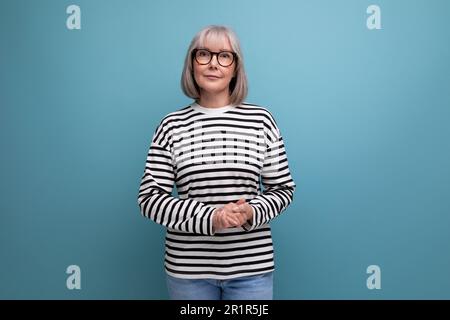 Geschäftsfrau mittleren Alters mit grauen Haaren und fröhlicher Pose vor einem hellen Studiohintergrund Stockfoto