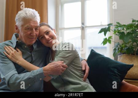 Enkelin umarmt ihren Großvater zu Hause. Stockfoto