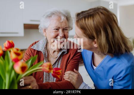 Seniorin und Krankenschwester mit Tulpenbouquet. Stockfoto