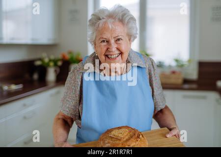 Porträt einer Seniorin mit frisch gebackenem Brot. Stockfoto