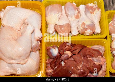 Hähnchenschenkel mit frischem rohem Hähnchen Hinterviertel und Schenkel und frische, ungekochte Hühnerleber, Muskelmagen und Herzen, selektiver Fokus auf frisches Leben Stockfoto