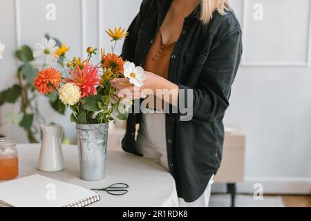 Nahaufnahme einer Frau, die Blumen in einer Vase arrangiert Stockfoto
